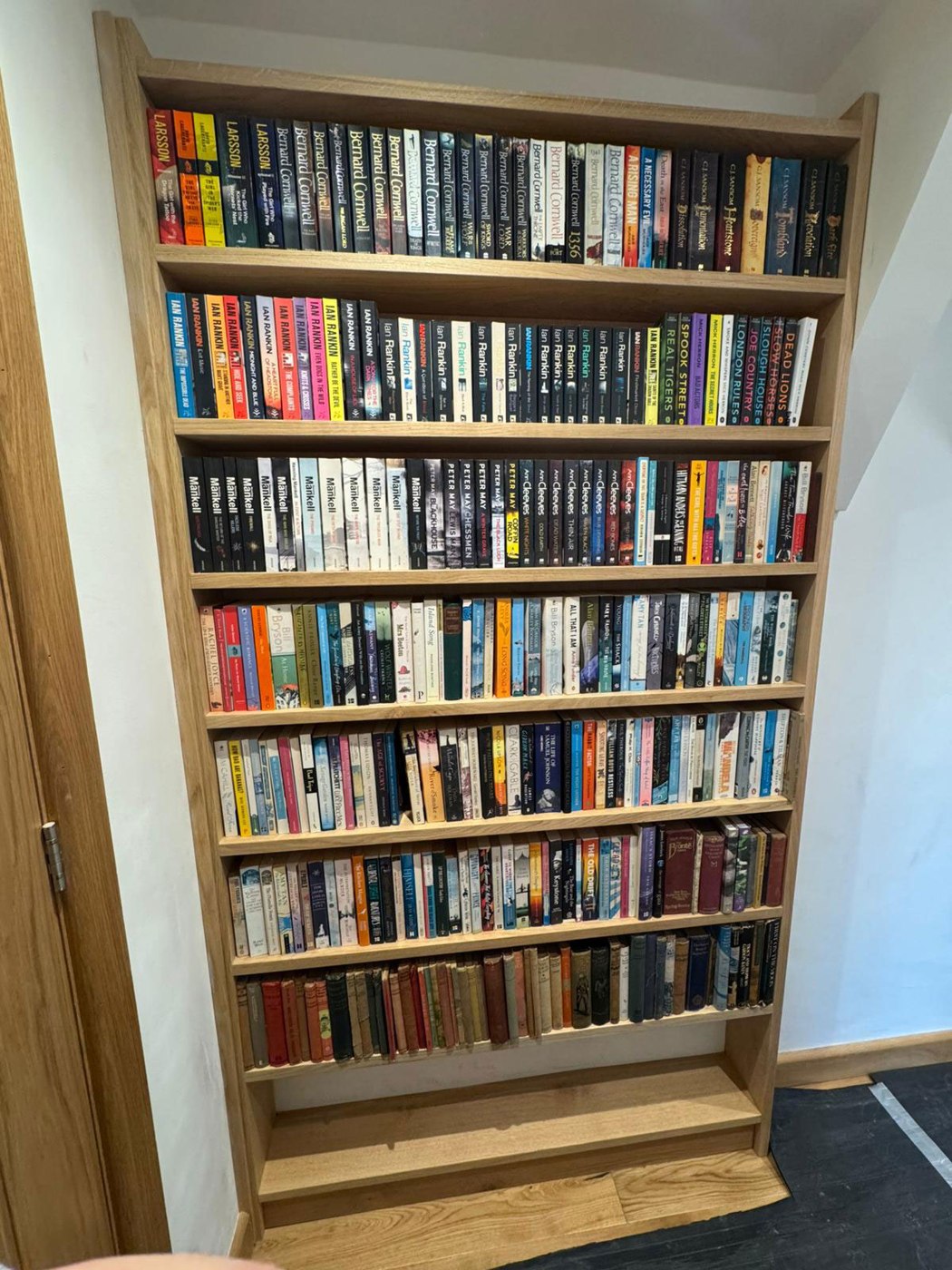 Fitted oak bookcase with shelving built around an alcove