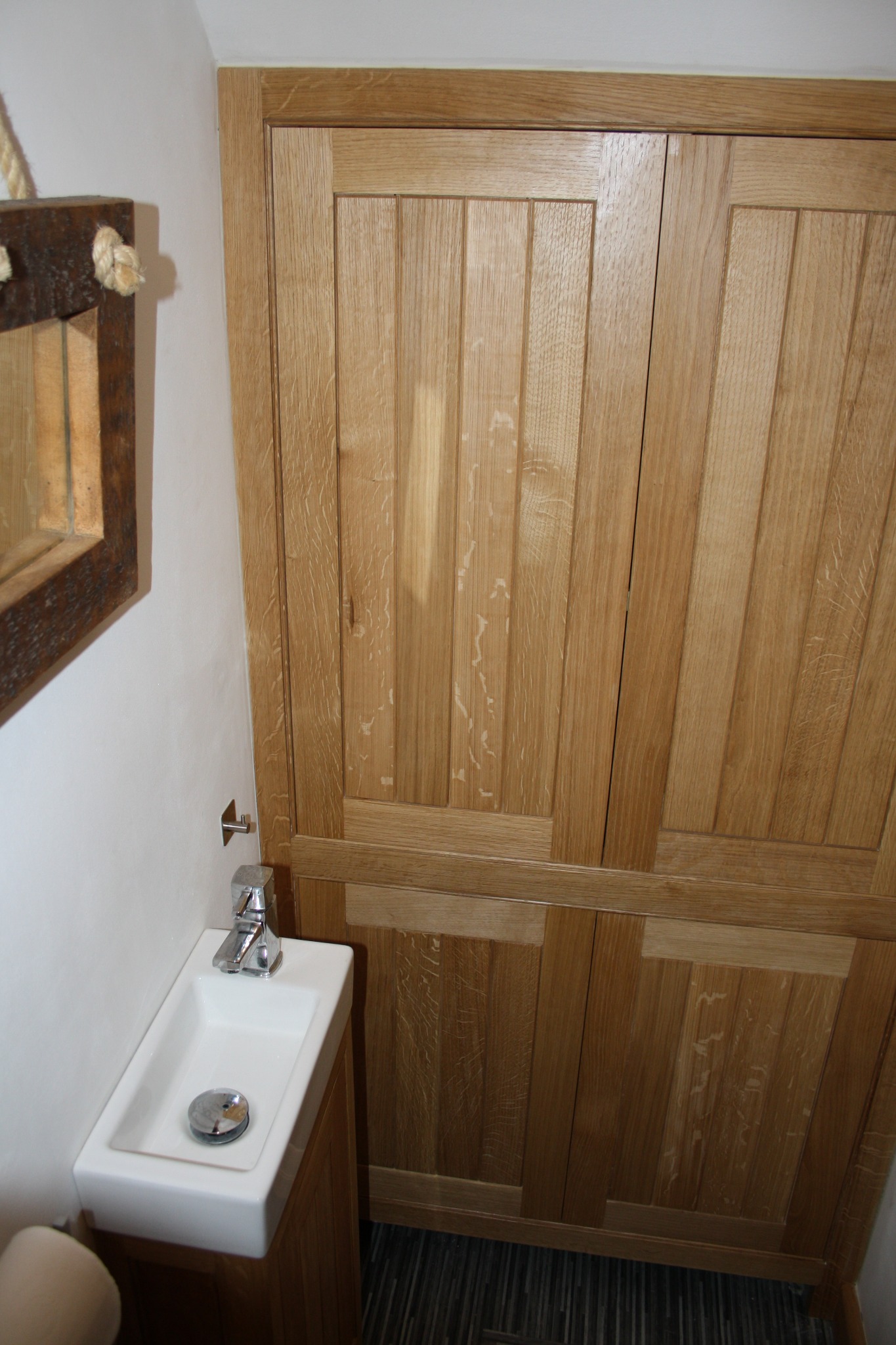 Oak cupboard doors with framed panels and distinctive natural grain beside a compact basin